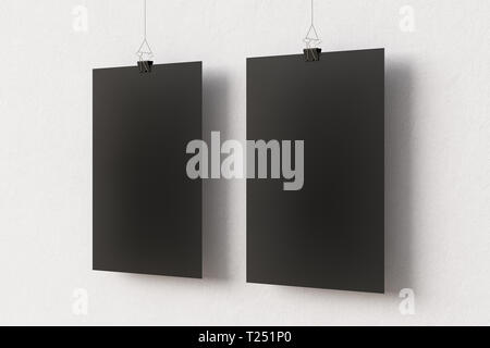 Deux affiches vierges en papier noir accrochées à une pince à reliure sur un fond de mur blanc Banque D'Images