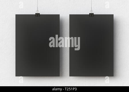 Deux affiches vierges en papier noir accrochées à une pince à reliure sur un fond de mur blanc Banque D'Images