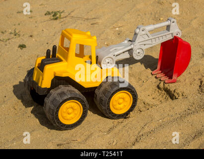 Excavatrice jaune jouet dans le sable, sur la plage. Les jouets du garçon - concept de droit Banque D'Images