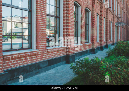 Immeuble de bureaux dans un style loft. De grandes fenêtres. Mur de brique rouge. Buissons verts sur la droite. La composition Perspective shot Banque D'Images