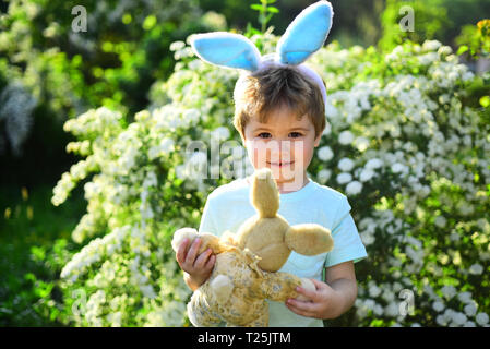 Kid lapin avec oreilles de lapin. Hare jouet. Petit garçon enfant en vert forêt. Vacances de printemps sur la chasse aux œufs de pâques. L'amour. Vacances en famille. Joyeuses Pâques Banque D'Images