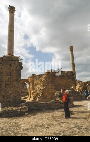 Tunisie, Tunis. 17 septembre, 2016. Slim woman avec un sac à dos prend des photos des ruines de l'antique Carthage Banque D'Images