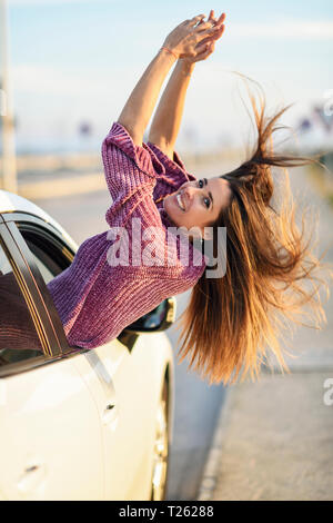 Portrait of happy woman leaning out of car window Banque D'Images
