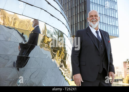 Portrait élégant dans la ville, à rire devant la façade miroir Banque D'Images