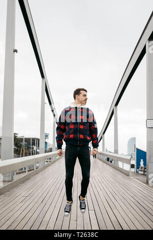 Jeune homme portant des vêtements décontractés sautant sur un pont du Havre Banque D'Images