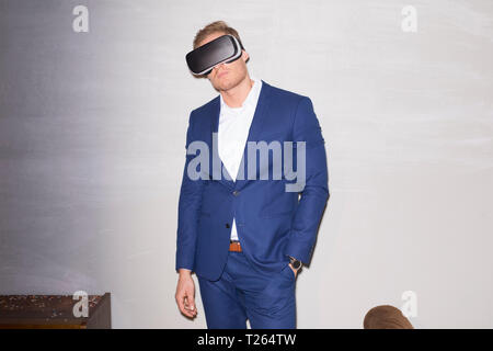 Jeune homme portant un costume bleu à l'aide de lunettes de réalité virtuelle Banque D'Images