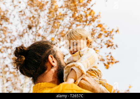 Père tenant sa fille dans la matinée, dans un parc en automne Banque D'Images