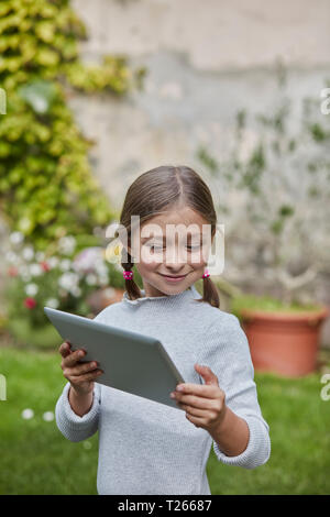 Smiling girl using tablet in garden Banque D'Images