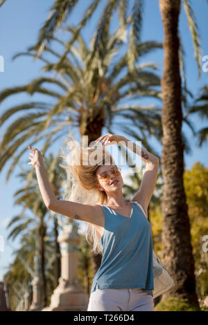 Jeune femme insouciante se déplaçant sous palm tree Banque D'Images