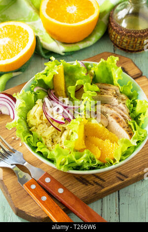 Menu de régime. Salade saine avec du poulet, des œufs crêpes, orange, salade verte et vinaigrette vinaigrette sur table en bois. Banque D'Images