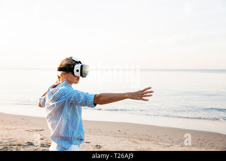 Femme blonde faire genre d'exercices de yoga sur une plage en Thaïlande avec des lunettes de réalité virtuelle 3D Banque D'Images