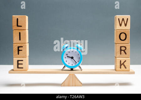 Réveil bleu entre les mots la vie et le travail sur les échelles. choix entre la vie et le travail. Le concept de l'attention accordée à la promotion des valeurs de la vie, Banque D'Images