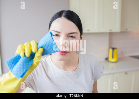 Portrain horizontale de la femme se tient et nettoie lenz d'appareil photo. Elle est très concentré sur cela. Fille est de le nettoyer avec un chiffon bleu. Elle a ses mains Banque D'Images