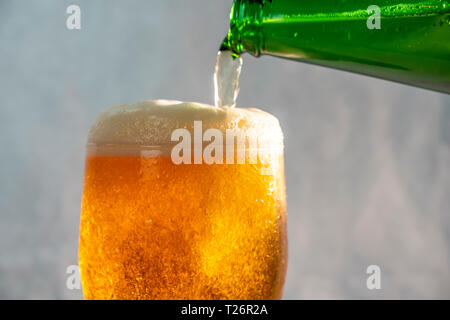 Servir la bière dans un verre d'une bouteille verte Banque D'Images