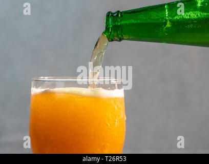Servir la bière dans un verre d'une bouteille verte Banque D'Images