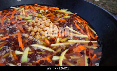 Plat national ouzbek pilaf dans un grand chaudron en fonte sur le feu Banque D'Images