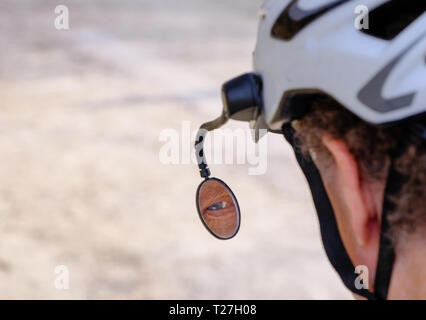 Vue d'un cycliste senior's eye reflétée dans le rétroviseur attaché à casque Banque D'Images