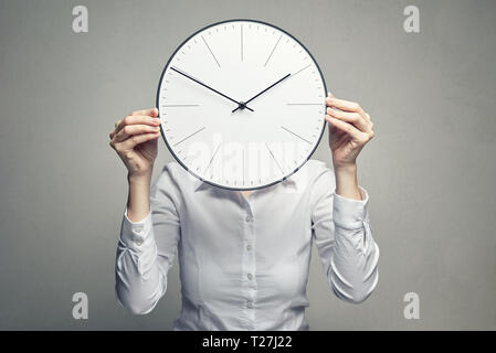 Femme d'affaires en blouse blanche couvrant son visage avec horloge Banque D'Images