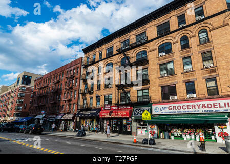 La ville de New York, USA - Le 29 juillet 2018 : épicerie avec des bouquets de fleurs dans sa vitrine à côté d'autres magasins et les gens autour à Harlem, Manhattan, New Banque D'Images