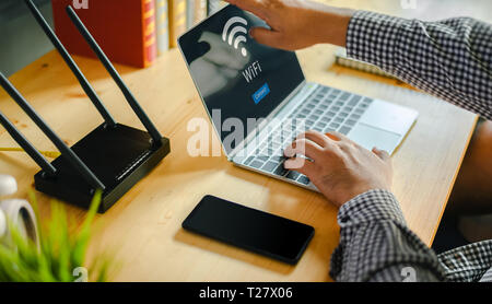 Jeune homme de la connexion wifi du routeur sur l'ordinateur portable pour Internet et les médias sociaux Banque D'Images