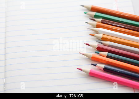 Crayons de couleur pour élèves et étudiants. Les crayons sont dispersées sur un tableau blanc et de se présenter dans un verre. Crayons pour les employés de bureau. Banque D'Images