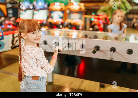 Happy girl au soccer sur table d'enfants game center. Female enfant s'amuser sur l'aire de l'intérieur. Kid joue sur la machine en football amusem Banque D'Images