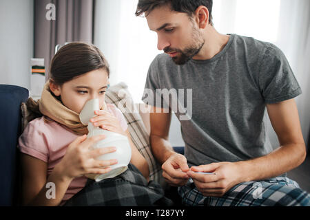 Photo de jeune homme s'asseoir sur le lit en plus de sa fille malade. Elle ne le traitement par inhalation. Guy controll il Banque D'Images