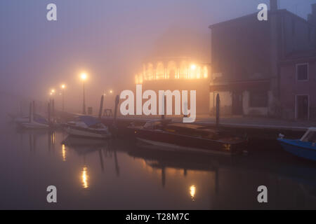 Venise, Italie, 05 février 2019 : canal vue nocturne sur l'île de Murano avec Basilica dei Santi Maria e Donato dans le brouillard à l'allumage. Banque D'Images