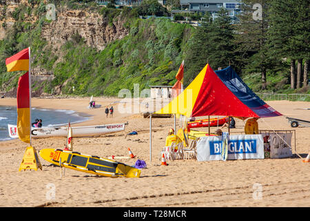 Surf sauvetage volontaires sur Newport Beach à Sydney, en Australie avec des drapeaux rouges et jaunes de plage et une tente ombragée Banque D'Images