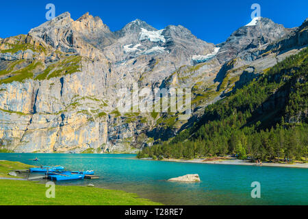 Célèbre lieu de loisirs et de voyages, de belles montagnes enneigées et le lac alpin avec des bateaux colorés, lac Oeschinensee, Oberland Bernois, Suisse, Euro Banque D'Images