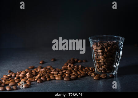 Les grains de café en verre sur fond sombre avec copie espace, faible image clé Banque D'Images
