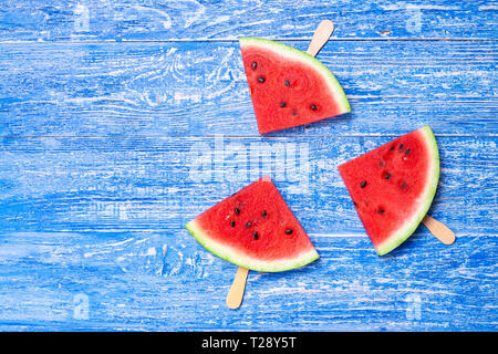 Tranche de pastèque fraîche sur un bâton. Le melon d'eau est coupé en forme de triangle. on blue background Banque D'Images