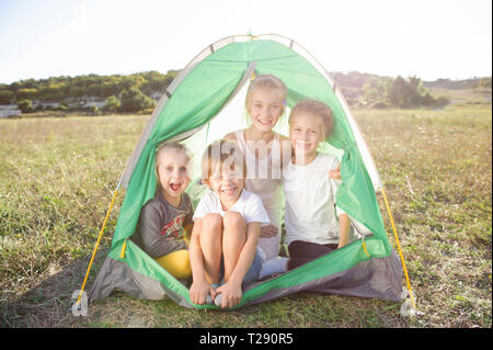 Groupe d'enfants heureux à l'intérieur de tente au cours de la randonnée reste en été grass field Banque D'Images