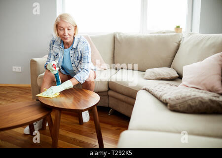 Femme mature dépoussiérage des table basse Banque D'Images