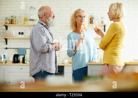 Cheerful friends drinking champagne in kitchen Banque D'Images