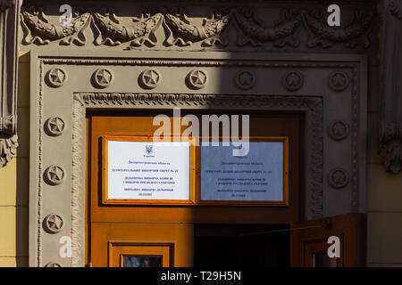 Dniepr, l'UKRAINE - 31 mars 2019 : Entrée de la place du bureau de vote dans le bâtiment universitaire. Élection du Président de l'Ukraine. Pavillon ukrainien volant près de la porte Crédit : Andrey Yanevich/Alamy Live News Banque D'Images