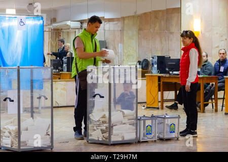 Dniepr, l'UKRAINE - 31 mars 2019 : un jeune homme met l'électeur un bulletin de vote dans l'urne. À côté du conteneur est sa femme et son enfant. Élection du Président de l'Ukraine. Des observateurs de partis politiques différents. Crédit : Andrey Yanevich/Alamy Live News Banque D'Images