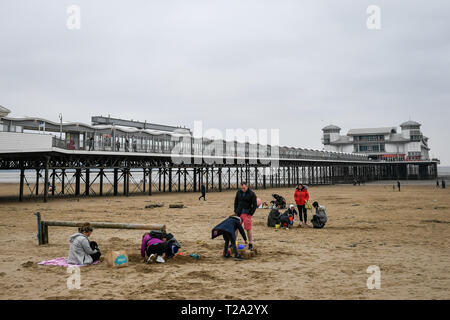 Les gens jouent à côté de la grande jetée sur la plage à Weston-super-Mare. Banque D'Images