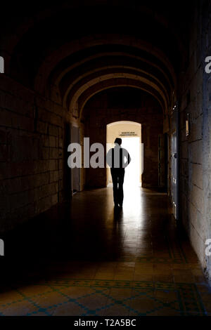 Figure solitaire, silhouetted, marchant à travers un couloir sombre. Banque D'Images