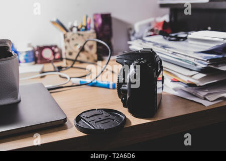 Un appareil photo Nikon générique sans marque visible sur une table sous une lampe de table au bureau à domicile ou en studio d'un blogger. Banque D'Images