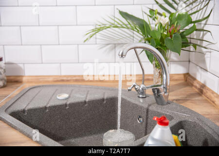 L'eau pure qui s'écoule de la grue en cuisine. Cuisine moderne Banque D'Images