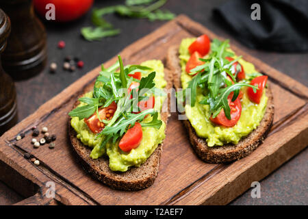 Végétarien ou Végétalien pain grillé avec purée d'avocat, roquette servi sur planche de bois Banque D'Images