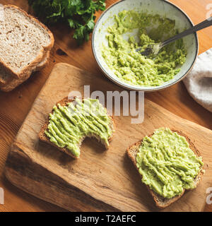 La purée d'avocat sur pain de grains entiers sur planche à découper en bois. Un petit-déjeuner sain, un brunch ou une collation. Toast à l'avocat par l'absence de dent. Culture Square Banque D'Images