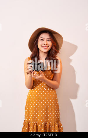 Portrait of smiling young woman taking photo avec l'inspiration et de porter cette robe. Girl holding retro camera. Model posing sur rond retour Banque D'Images