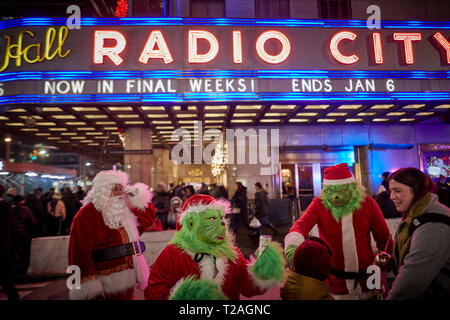 Décorations de Noël Radio City buskers habillée en père et le Grinch à astuces , la 6ème Avenue, Manhattan, New York la nuit Banque D'Images