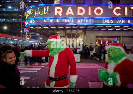 Décorations de Noël Radio City buskers habillée en père et le Grinch à astuces , la 6ème Avenue, Manhattan, New York la nuit Banque D'Images