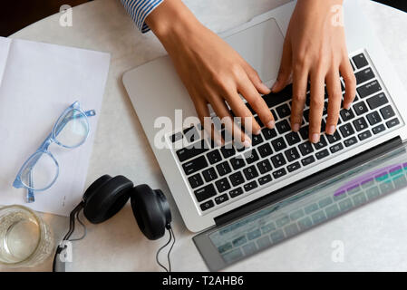 High angle view of young woman's hands typing on laptop Banque D'Images