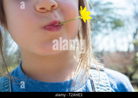 Fille avec fleur jaune dans la bouche Banque D'Images