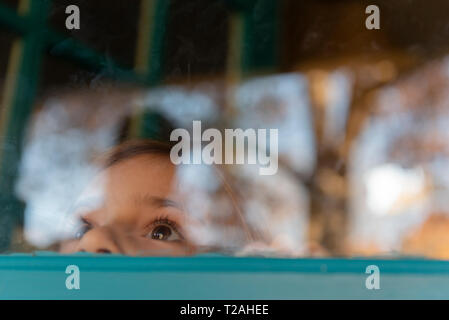 Girl peering through window Banque D'Images