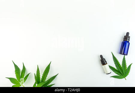 Feuilles de cannabis marijuana et bouteilles d'huile isolé sur blanc Vue de dessus Banque D'Images